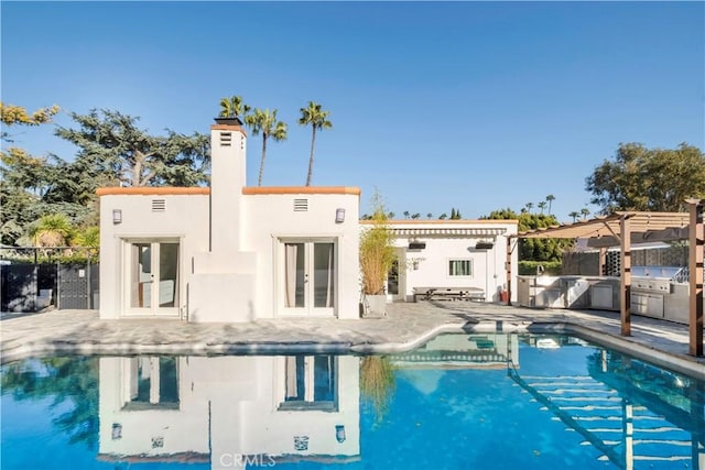 back of property with an outdoor kitchen, french doors, a pergola, and fence