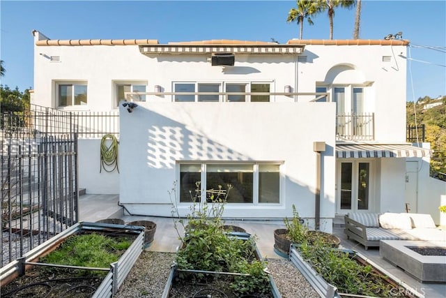 rear view of house featuring stucco siding, french doors, a balcony, and fence