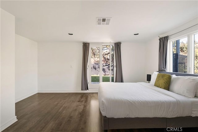 bedroom with wood finished floors, visible vents, and baseboards