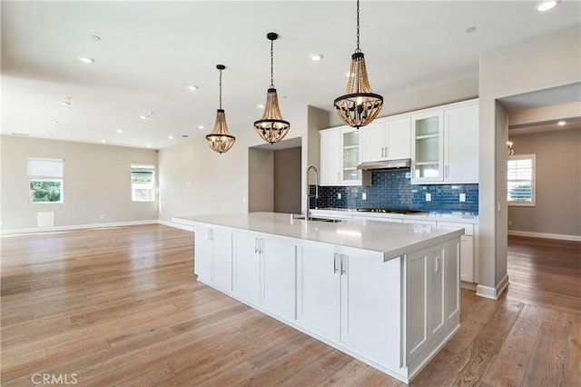 kitchen with an inviting chandelier, white cabinets, gas cooktop, and a sink