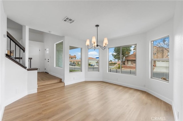 unfurnished dining area featuring visible vents, a notable chandelier, stairway, light wood finished floors, and baseboards