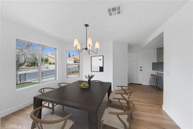 dining space featuring a chandelier, visible vents, light wood finished floors, and baseboards