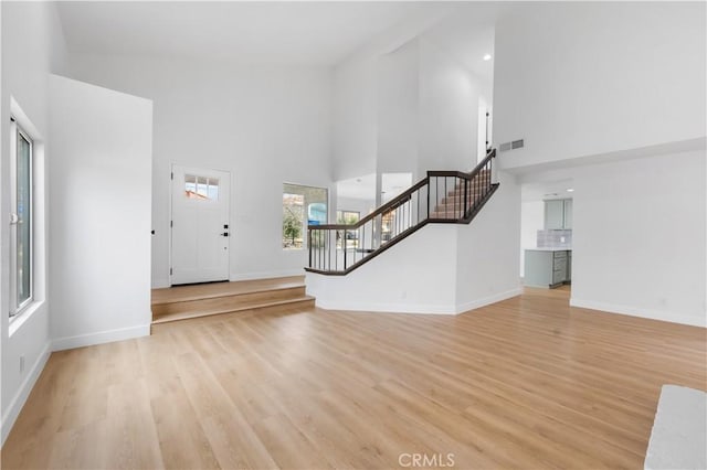 foyer featuring visible vents, light wood-style flooring, stairway, and baseboards