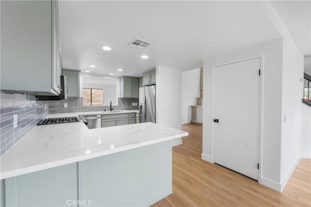 kitchen featuring a sink, appliances with stainless steel finishes, light wood-style flooring, and gray cabinets