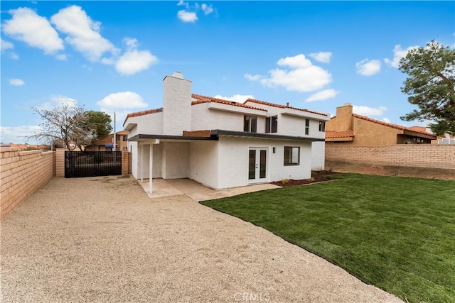 back of house with a tiled roof, fence private yard, stucco siding, french doors, and a lawn