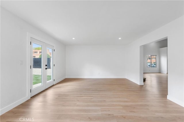 spare room featuring plenty of natural light, baseboards, and light wood-type flooring