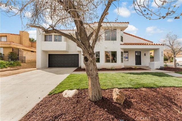 mediterranean / spanish home with stucco siding, a front yard, driveway, and fence