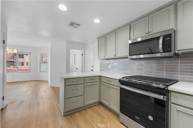 kitchen with visible vents, light countertops, decorative backsplash, a peninsula, and stainless steel appliances