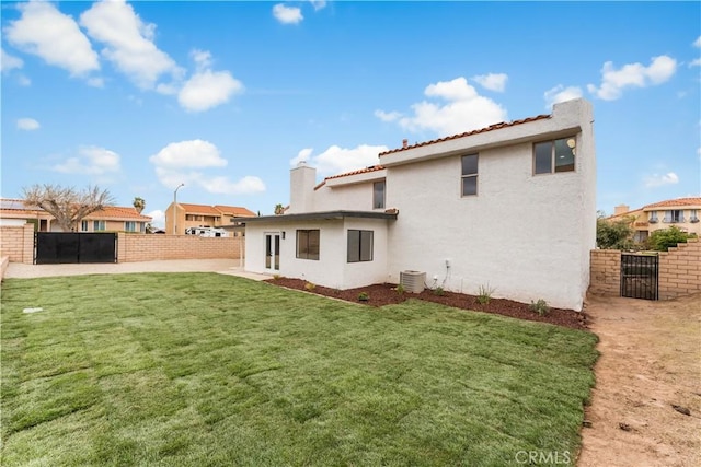 rear view of house featuring cooling unit, fence, a yard, and stucco siding