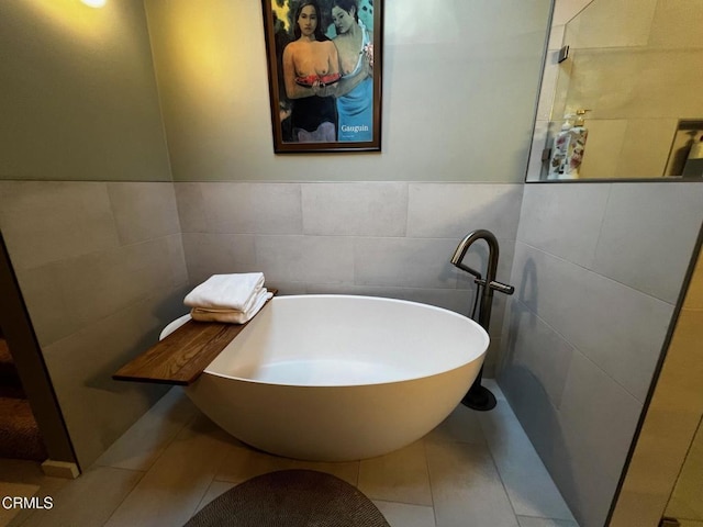 bathroom featuring tile patterned flooring, a freestanding bath, and tile walls