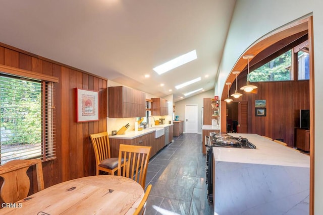 dining room with lofted ceiling with skylight and wood walls