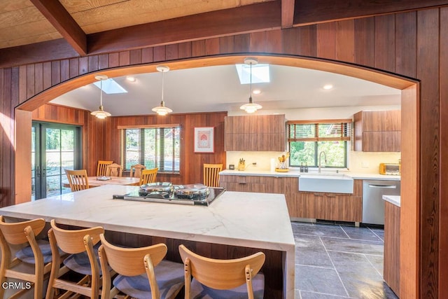 kitchen featuring wooden walls, stovetop, arched walkways, a sink, and dishwasher