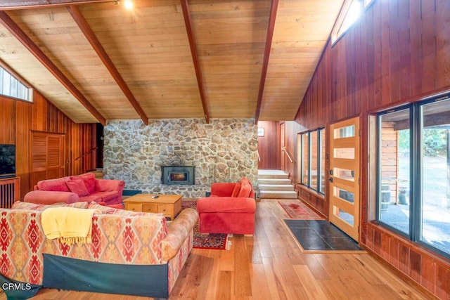 living room with wooden walls, beamed ceiling, stairs, hardwood / wood-style floors, and a fireplace