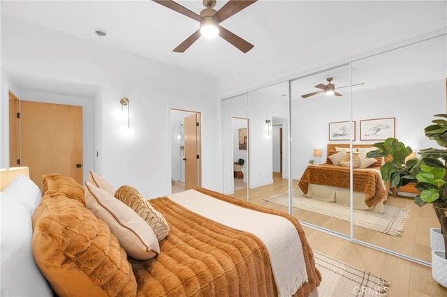 bedroom with a ceiling fan, wood finished floors, and a closet