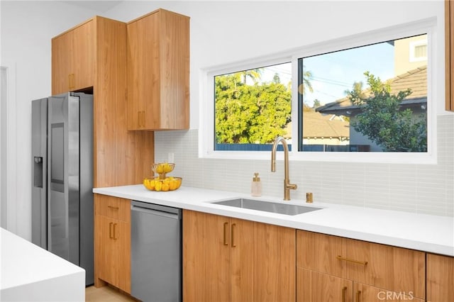 kitchen featuring backsplash, light countertops, appliances with stainless steel finishes, modern cabinets, and a sink