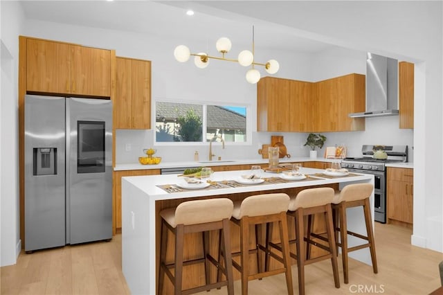 kitchen featuring a sink, brown cabinets, appliances with stainless steel finishes, and wall chimney exhaust hood