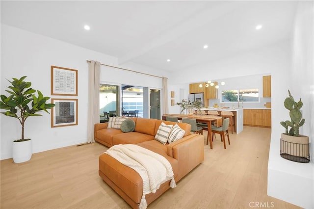 living room featuring beam ceiling, recessed lighting, a healthy amount of sunlight, and light wood-type flooring