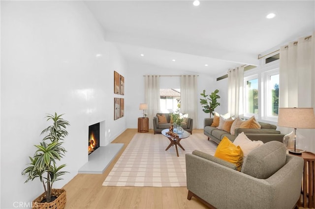 living area with recessed lighting, a warm lit fireplace, light wood-style flooring, and vaulted ceiling with beams