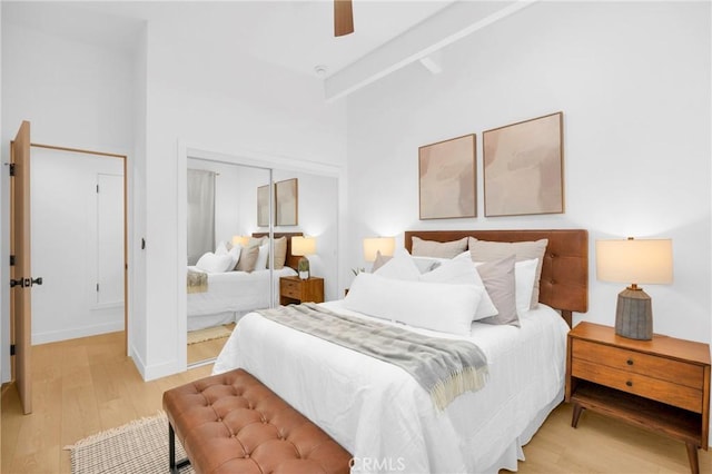 bedroom featuring a high ceiling, baseboards, light wood-type flooring, and ceiling fan