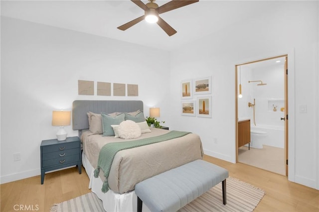 bedroom featuring ensuite bath, light wood-style flooring, baseboards, and ceiling fan