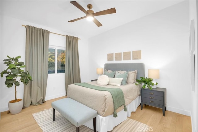 bedroom with light wood-style flooring, a ceiling fan, and baseboards