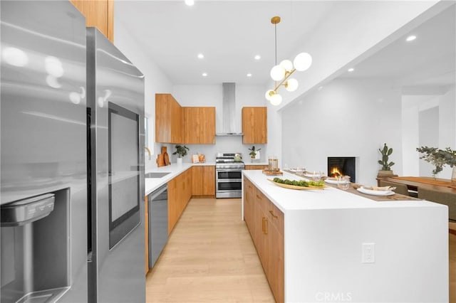 kitchen with a center island, light countertops, appliances with stainless steel finishes, modern cabinets, and wall chimney exhaust hood