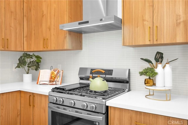 kitchen with gas stove, backsplash, light countertops, and wall chimney range hood