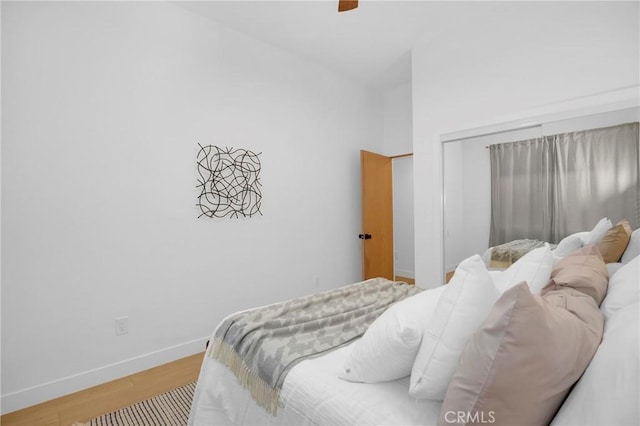 bedroom featuring a closet, a ceiling fan, baseboards, and wood finished floors