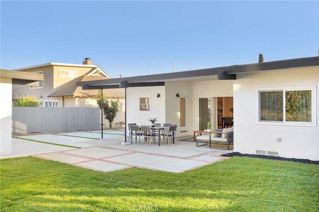 back of property featuring a patio, a lawn, visible vents, and stucco siding