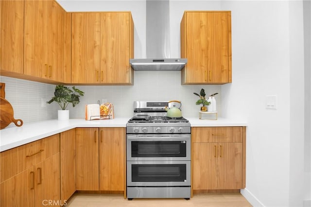 kitchen featuring modern cabinets, double oven range, wall chimney range hood, backsplash, and light countertops