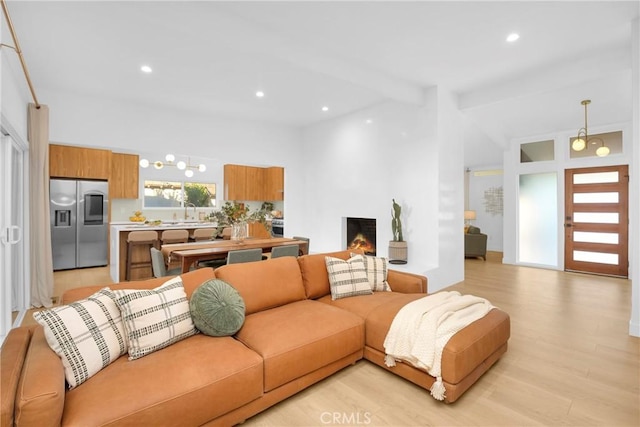 living room with recessed lighting, light wood-style flooring, and vaulted ceiling with beams