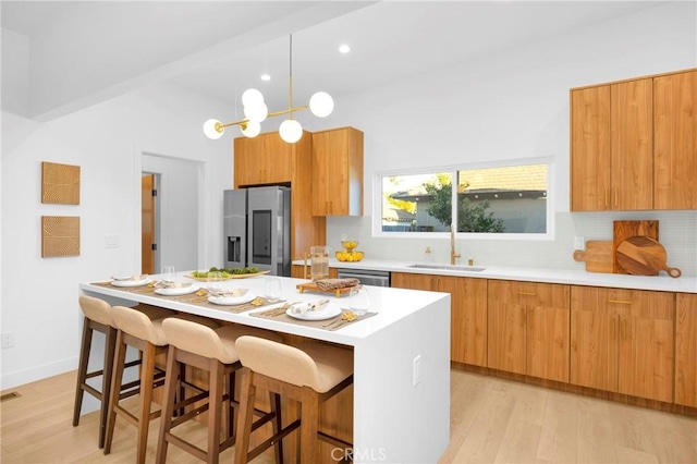 kitchen with brown cabinetry, decorative backsplash, appliances with stainless steel finishes, and a sink