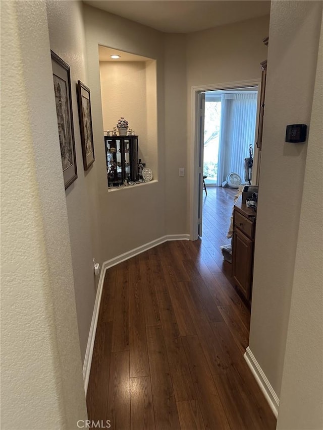 hall with baseboards and dark wood-type flooring