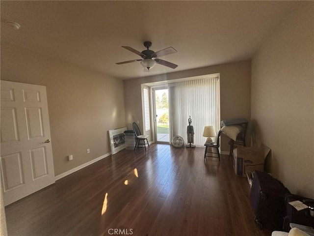 sitting room featuring baseboards, a ceiling fan, and dark wood-style flooring