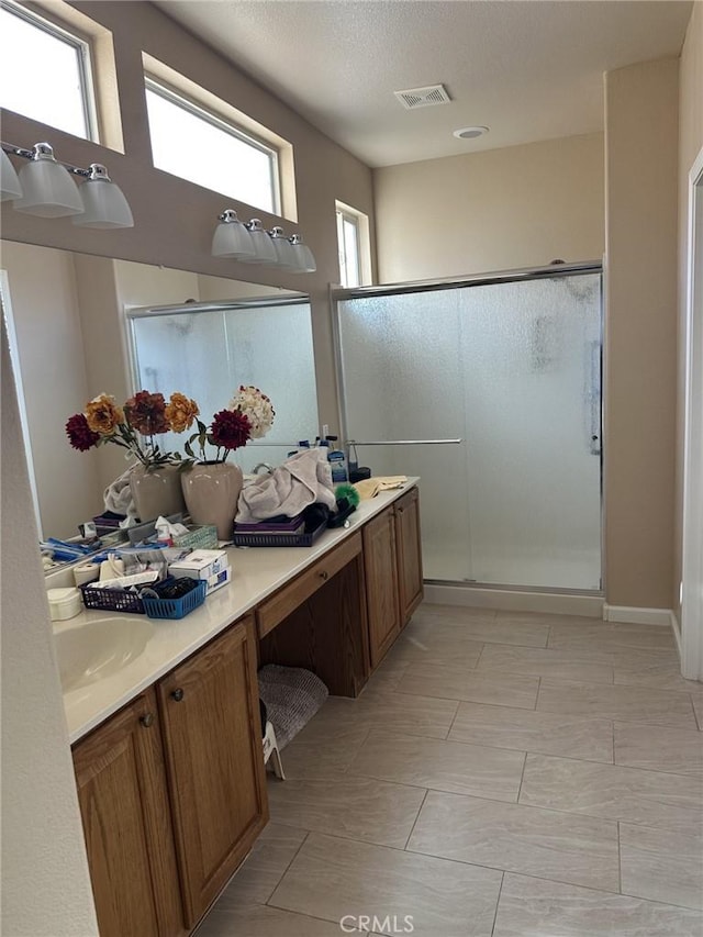 full bathroom featuring visible vents, a stall shower, vanity, and a textured ceiling