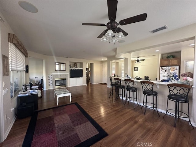 kitchen with visible vents, dark wood-type flooring, ceiling fan, a breakfast bar area, and freestanding refrigerator