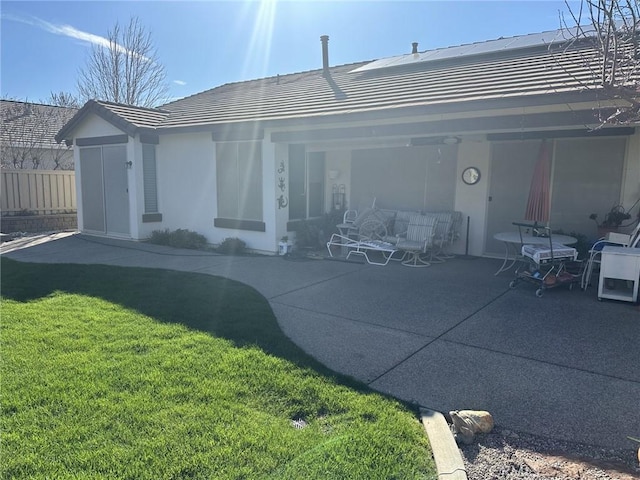 rear view of property with a patio, fence, solar panels, a yard, and a tile roof