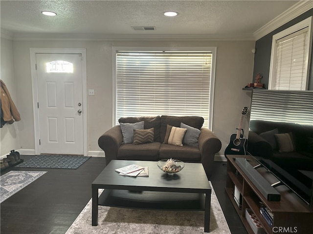 living room featuring visible vents, baseboards, a textured ceiling, and ornamental molding