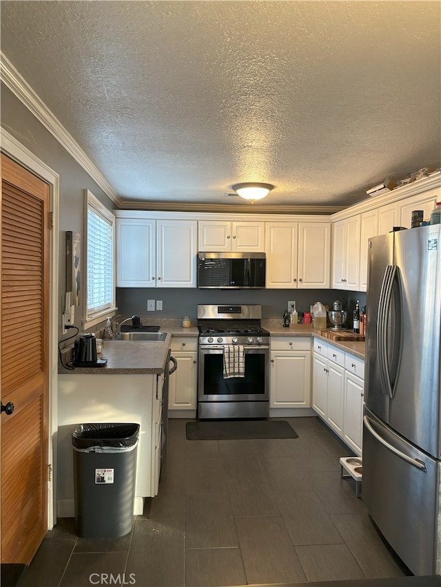 kitchen featuring a sink, a textured ceiling, stainless steel appliances, white cabinets, and crown molding