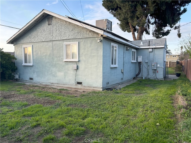 rear view of property with crawl space, a yard, stucco siding, and fence