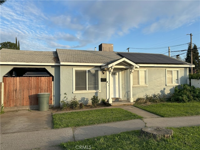 view of front of home featuring solar panels, fence, and stucco siding