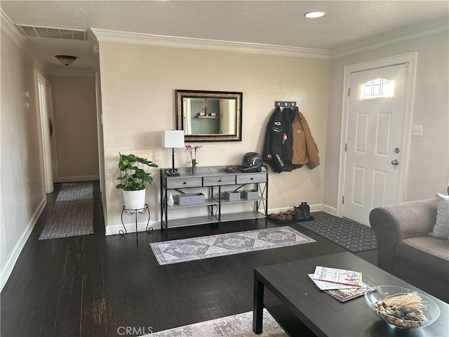 interior space with visible vents, ornamental molding, hardwood / wood-style flooring, a textured ceiling, and baseboards