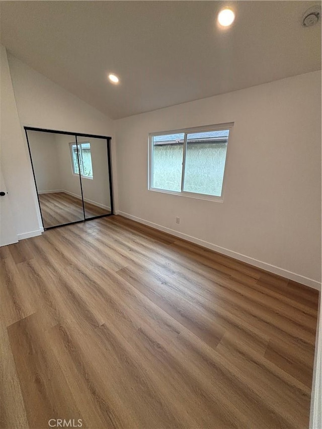 unfurnished bedroom with recessed lighting, wood finished floors, baseboards, and vaulted ceiling