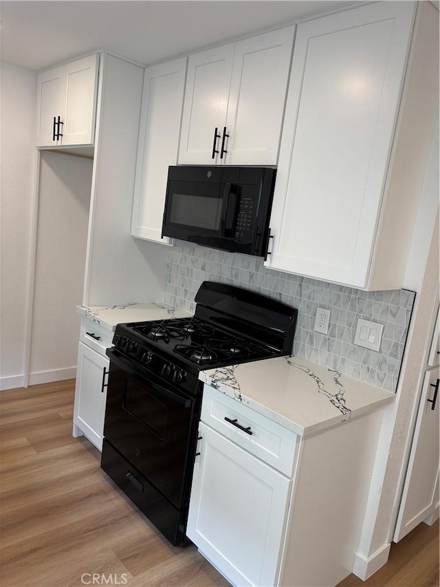 kitchen with light wood finished floors, white cabinetry, black appliances, and light countertops