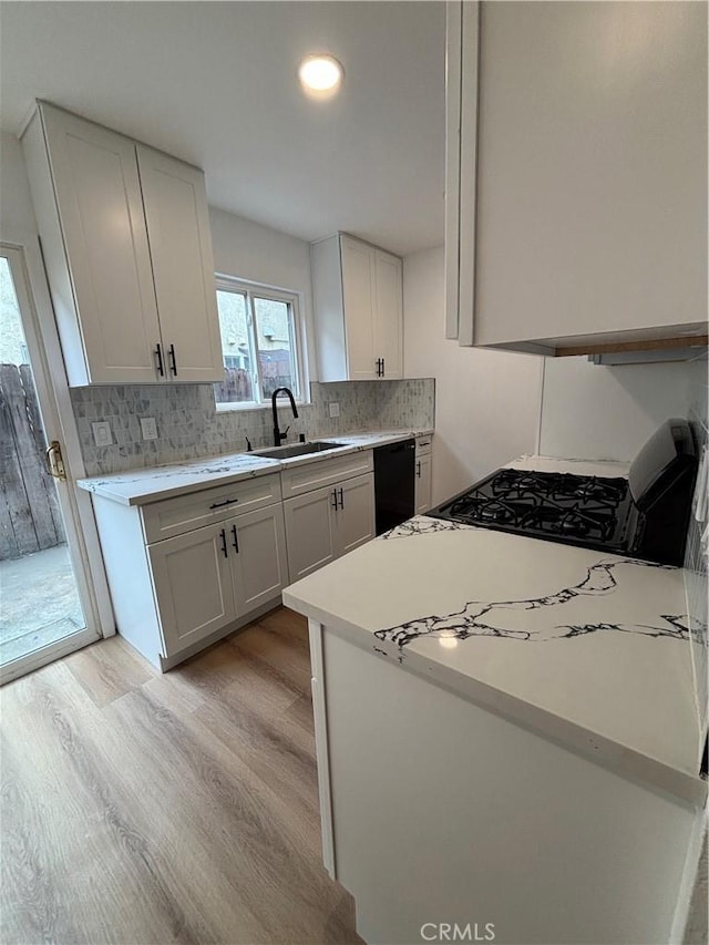 kitchen with tasteful backsplash, light wood-style flooring, dishwasher, and light countertops