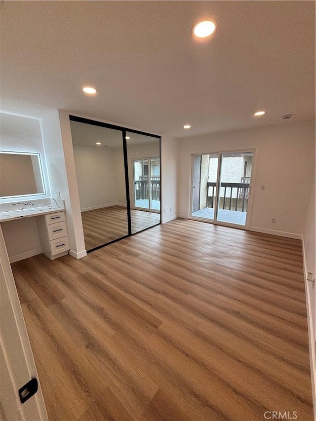 interior space with recessed lighting, light wood-type flooring, baseboards, and access to outside