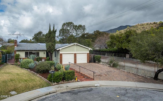 single story home with stucco siding, fence, a mountain view, a front yard, and a garage