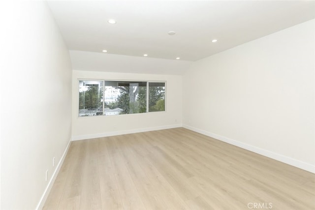 empty room featuring light wood-style floors, recessed lighting, baseboards, and vaulted ceiling