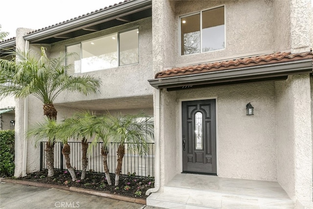 view of exterior entry featuring stucco siding and a tiled roof