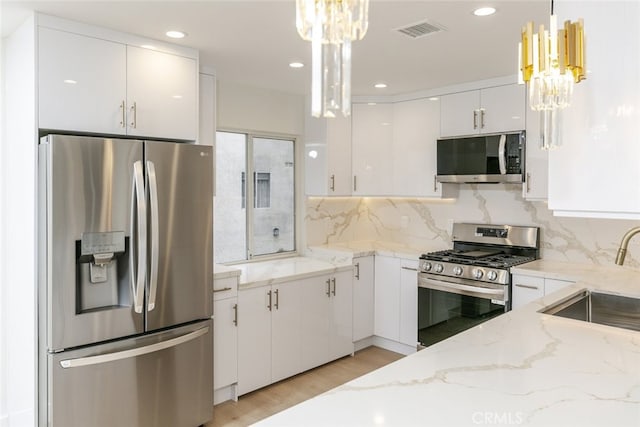 kitchen featuring a sink, a notable chandelier, white cabinetry, and stainless steel appliances